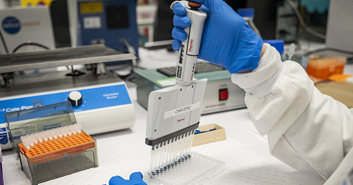 Someone working with vials in a lab.